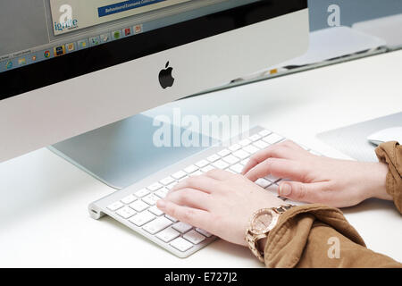 Female hands typing on the keyboard of an Apple Imac computer. Stock Photo