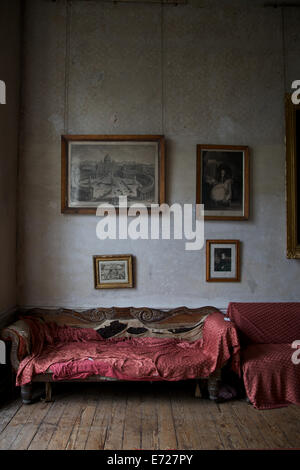 The interior of a old house with vintage furniture and old picture frames hung on the walls. Stock Photo