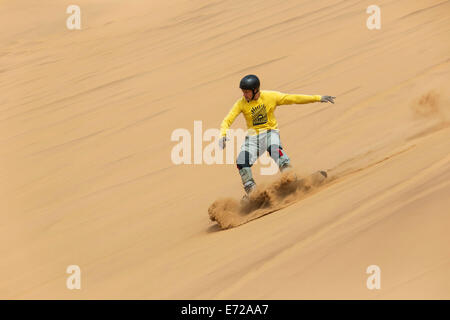 Sand boarding in the dunes of the Namib Desert, near Swakopmund, Namibia Stock Photo
