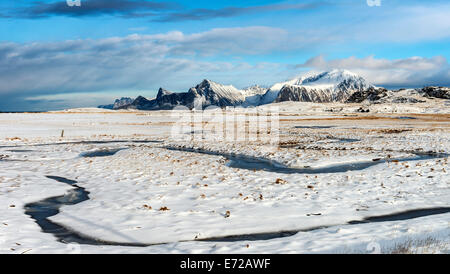 A frozen stream meandering through the snow at Fredvang on the Lofoten islands Stock Photo