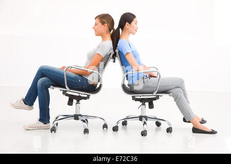 Two businesswoman sitting in chairs to back Stock Photo