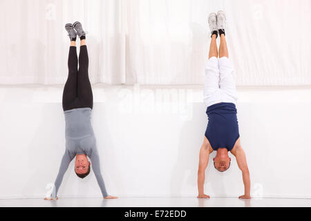 Man and woman doing handstand exercise in gym Stock Photo