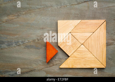 a missing piece in a square built from tangram pieces, a traditional Chinese puzzle game, slate rock background Stock Photo