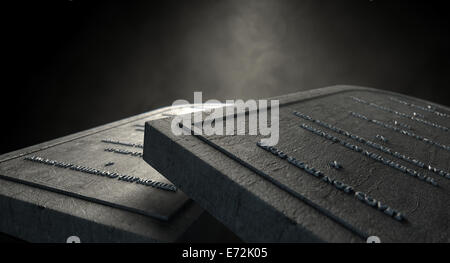 Two representative stone tablets with the ten commandments inscribed on them on an isolated dark ethereal background Stock Photo