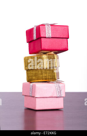 Three colorful gift boxes in row on wooden table, isolated on white background. Stock Photo