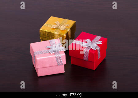 Three colorful gift boxes on wooden table. Stock Photo