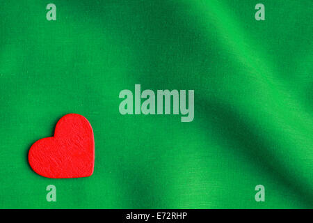 Valentine's day background. Red wooden decorative heart on abstract green wavy folds cloth or textile elegant material Stock Photo
