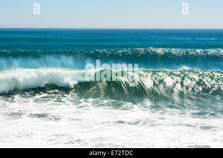 A beautiful and powerful turquoise wave in high winds curls while white spray mist forms and at its crest in Huntington Beach. Stock Photo