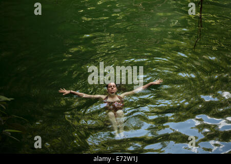 A woman swims in Xcanche Cenote near  the Mayan city of Ek Balam, Yucatan Peninsula, Mexico, August 10, 2014.  Cenotes are a geo Stock Photo