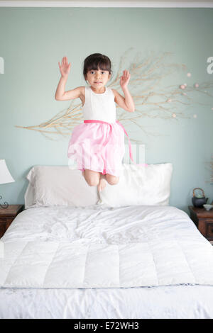 Girl (6-7) jumping on bed