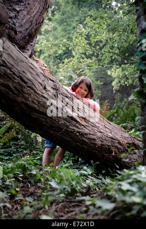 Portrait of smiling girl (6-7) leaning against tree trunk in forest Stock Photo