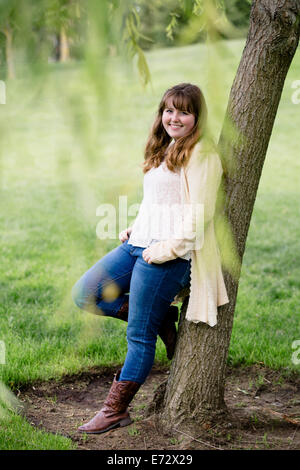 Portrait of teenage girl (13-15) leaning against tree Stock Photo