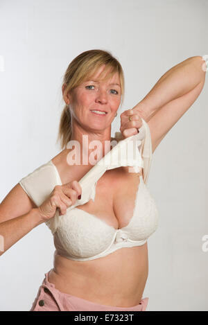 Woman getting dressed pulling shirt over her head Stock Photo