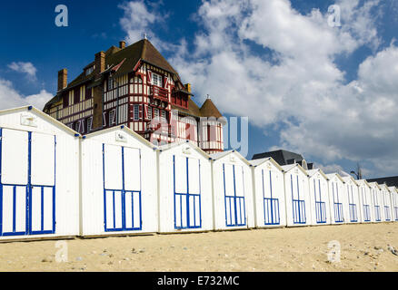 White beach cabins in a row on French coast with a beautiful big old building above, France, Normandy Stock Photo