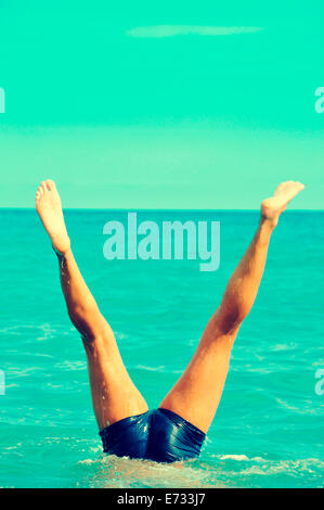 a young man doing a handstand in the sea Stock Photo