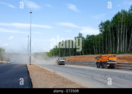 Street sweepers with clouds of dust at the road construction Stock Photo