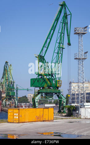 Yellow metal cargo container and green crane stand in port of Varna Stock Photo