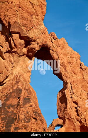 Near-full moon rising through an arch, Valley of Fire State Park, Nevada, United States of America, North America Stock Photo