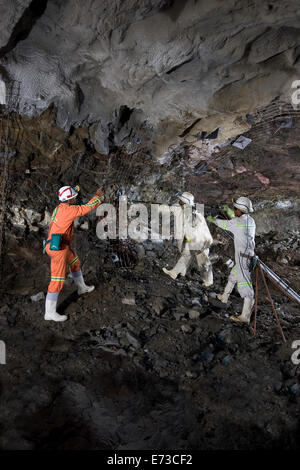 Drilling holes before rock bolting steel mesh roof safety support - before cementing and blasting again inside new platinum mine portal. South Africa Stock Photo