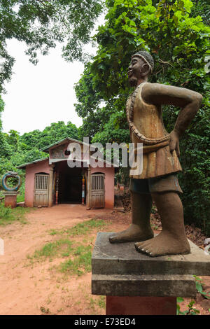 Africa, Benin, Ouidah. Painted concrete figure of Xevioso deity in front of building in Kpasse Sacred Forest. Stock Photo