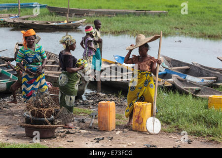 Africa, Benin, Ganvie. Women gathered on shore near dugout canoes. Stock Photo