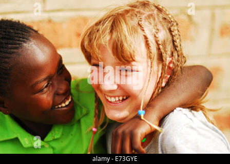 Kenya, Kakamega, black and white girls hugging as friends (MR). Stock Photo