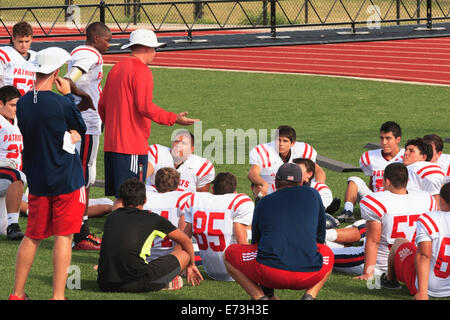 American high school football coach talking with junior varsity football team during game half-time Stock Photo