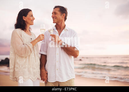 Happy Romantic Mature Couple Drinking Champagne on the Beach at Sunset. Vacation Travel Retirement Anniversary Celebration. Stock Photo