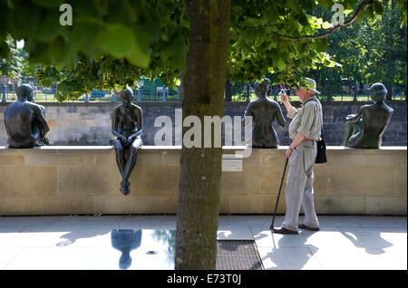 Germany, Berlin, Mitte, elderly man photographing bronze statues on the bank of the Spree River called Three Girls and a Boy. Stock Photo