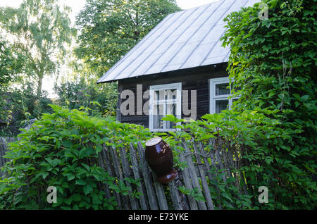 old country style house with windows and wooden fence with clay jug Stock Photo