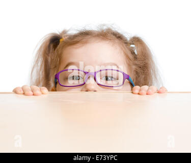 Funny girl in eyeglasses hiding behind a table Stock Photo