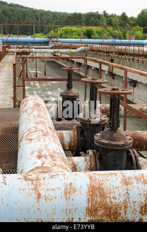 Rusty taps valves gate and pipes in water treatment plant and dirty liquid bubble. Stock Photo