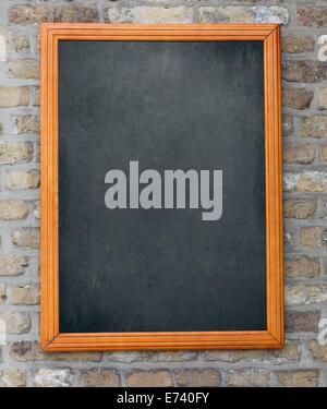 Aged blackboard hanging on brick wall as a background for your menu Stock Photo