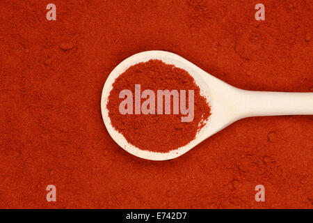 A wooden spoon lies on paprika powder forming a background Stock Photo