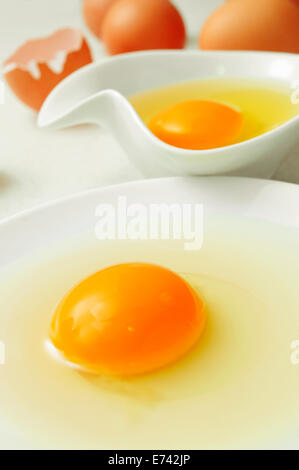 closeup of a plate and a bowl with cracked chicken eggs in a kitchen worktop Stock Photo