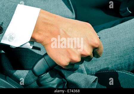 closeup of a man in suit pulling the hand brake of a car Stock Photo