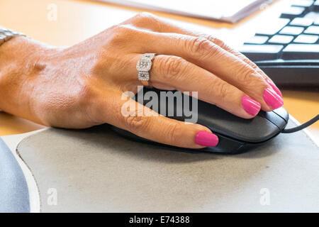 Mature lady's hand on computer mouse Stock Photo