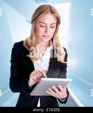Portrait of beautiful serious business woman using touchpad, modern electronic technology, working in the office Stock Photo
