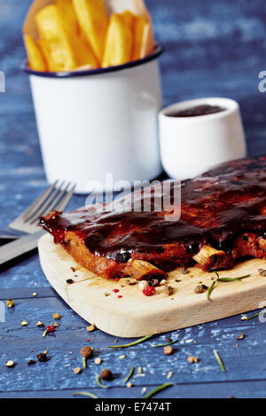Barbecue ribs with sauce and fires on wooden table, rustic table Stock Photo