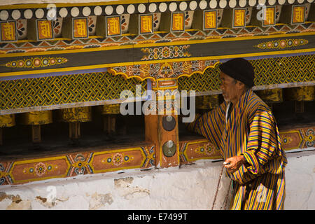 Eastern Bhutan, Trashi Yangtse, Chorten Kora, traditionally dressed man turning prayer wheels Stock Photo