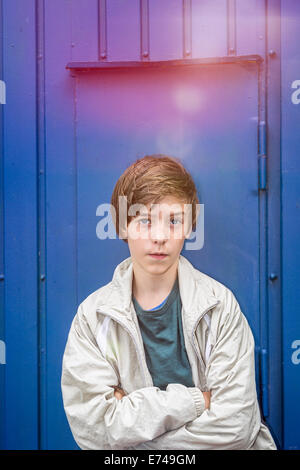 portrait of a teenager boy in front of a blue wall. Stock Photo