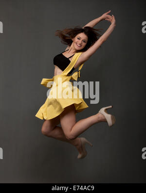 Beautiful young dancer jumping on a gray background Stock Photo