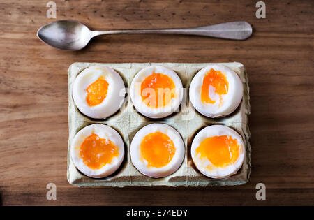 Half a dozen soft boiled eggs in a crate cardboard box. Stock Photo