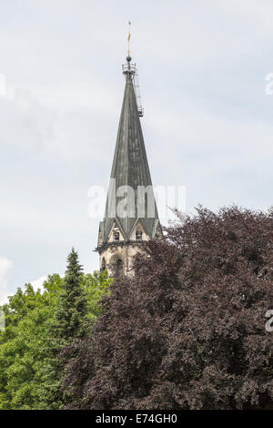 steeple behind a red tree in summer Stock Photo