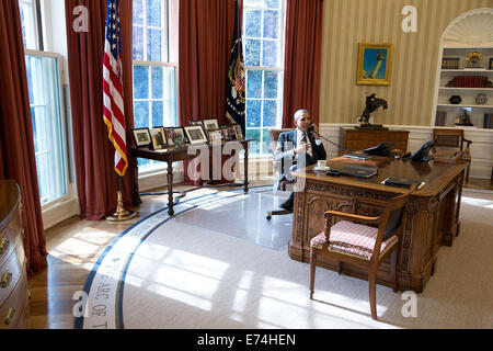 President Barack Obama talks on the phone with House Speaker John Boehner, R-Ohio, to discuss immigration reform, in the Oval Of Stock Photo