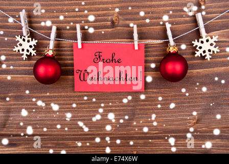 Red Label in the Snow Hanging on a Line with the German Words Frohe Weihnachten which means Merry Christmas Stock Photo