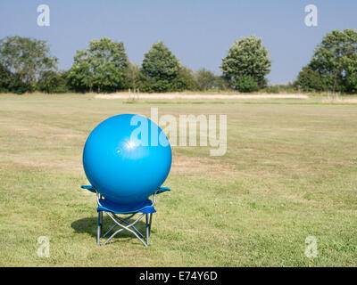 modern art, a blue ball on a blue chair in a green field Stock Photo