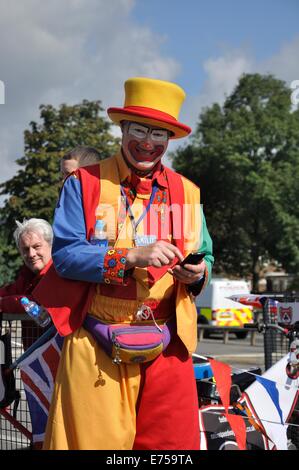Gorton, Manchester, UK. 7th Sep, 2014. Gorton Carnival Parade on way to Debdale Park, with a stop on Tesco car park, Gorton, for several of the groups in the parade to perform for spectators.-'Smilie' the clown on stilts, smiles at camera Stock Photo