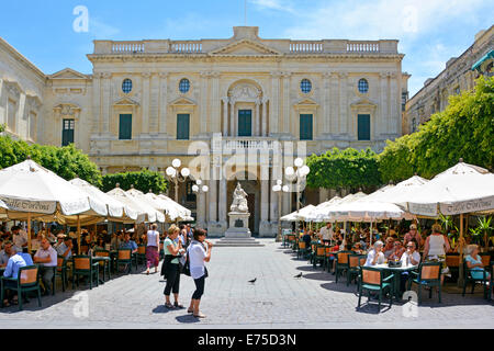 Rows of white parasols shading customers from hot sun cafe alfresco Republic Square Maltese National Library & statue Queen Victoria Valletta Malta Stock Photo