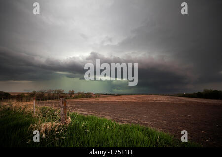 A set of wall clouds near an inflow notch on a hook-echo thunderstorm over a fallow field. Stock Photo